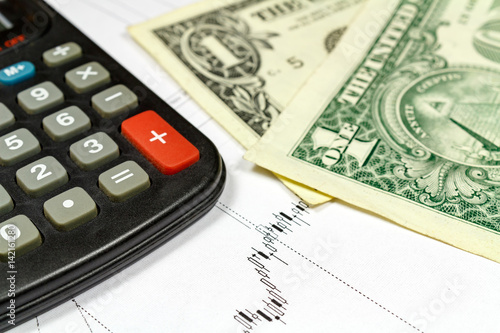 Fragment of electronic calculator and US dollars banknotes on the background of currency growth schedule