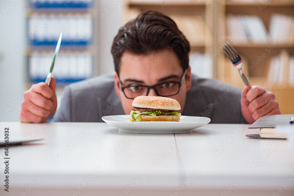 Hungry funny businessman eating junk food sandwich