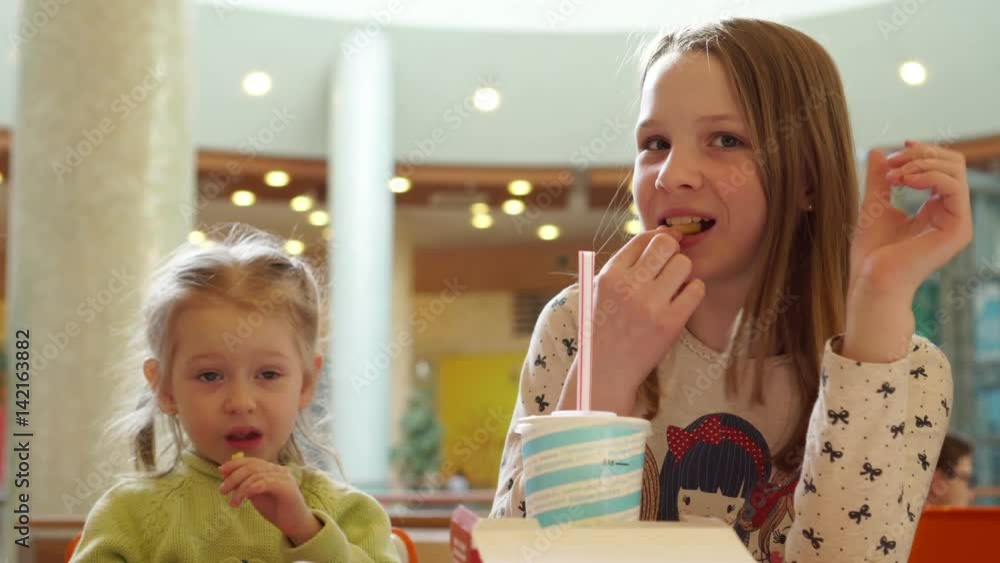 Cute little kid girls portrait funny eating in fast food court in a ...