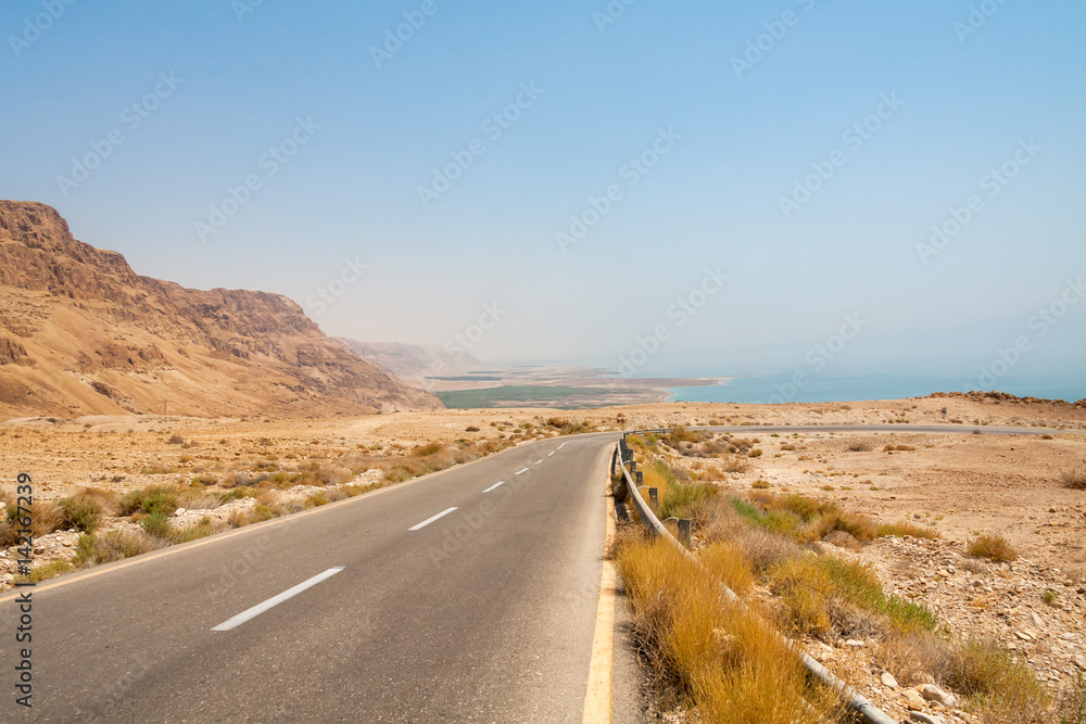 Steep turn of descend highway in Judean desert with Dead Sea in background. Metzoke Dragot, Israel.
