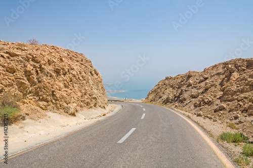 Steep turn of descend highway between mountain walls in Judean desert with Dead Sea in background. Metzoke Dragot, Israel.
 photo