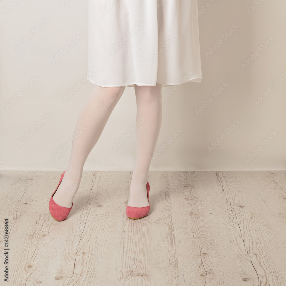 Female legs in white tights, skirt and ballet flats on a white background. Female legs in white tights, skirt and ballet flats on a white background.
