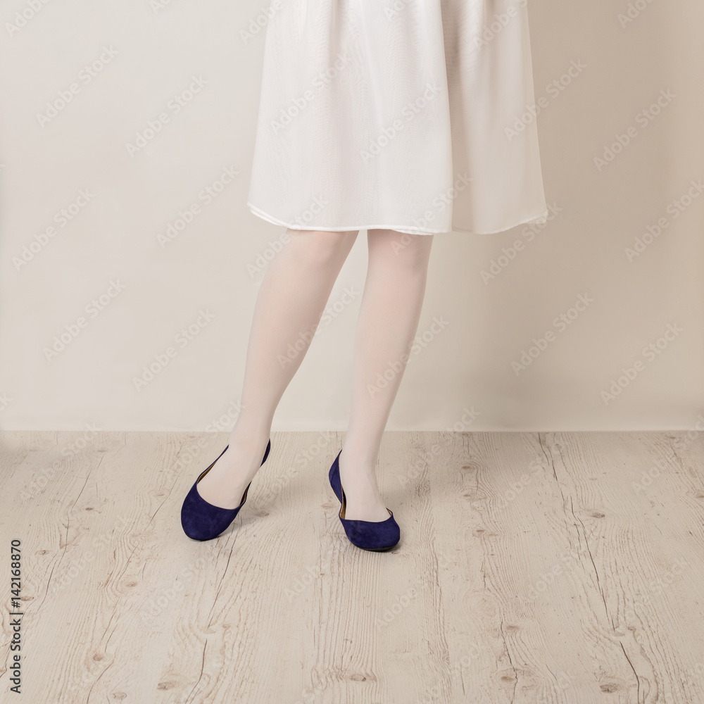 Female legs in white tights, skirt and ballet flats on a white background. Female legs in white tights, skirt and ballet flats on a white background.