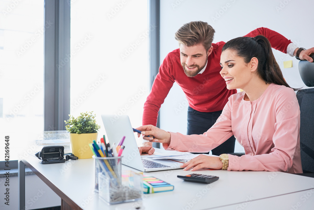 Two happy employees working with laptop at office desk Two happy employees working with laptop at office desk