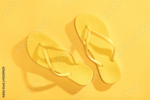 Close-up top view of comfortable yellow flip-flops on yellow background