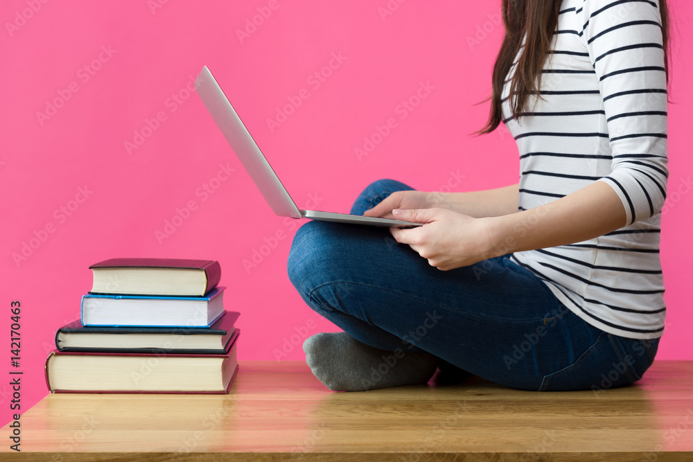Fototapeta premium Attractive caucasian girl studying for her exams at home, student sitting on her desk with laptop in her lap