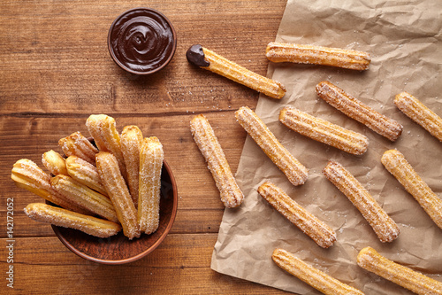 Churros traditional Spain culture breakfast or lunch sweet dough dessert baked pastry street fast food snack with chocolate dipping on rustic wooden table background. Flat lay top view