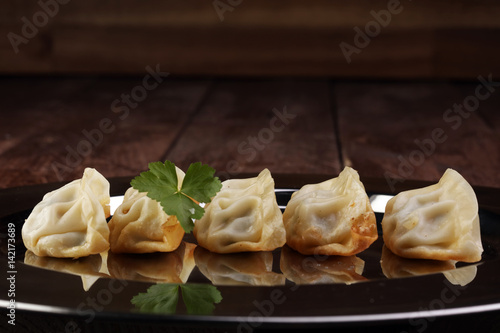 A plate of Japanese gyoza dumplings sitting on a rustic wooden table. photo