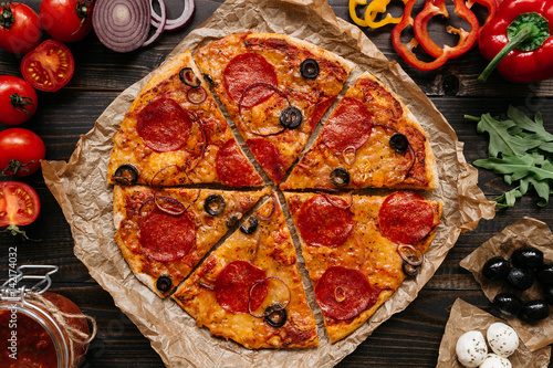 Fresh delisious pizza with pizza ingredients on the wooden table, top view