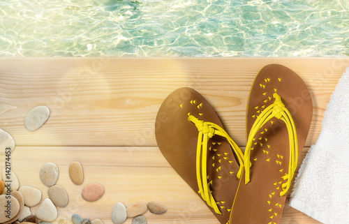 Summer beach vacation, flip flops, towel and sea pebbles on wood deck