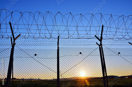 Fence with barbed wire on the sky background.
