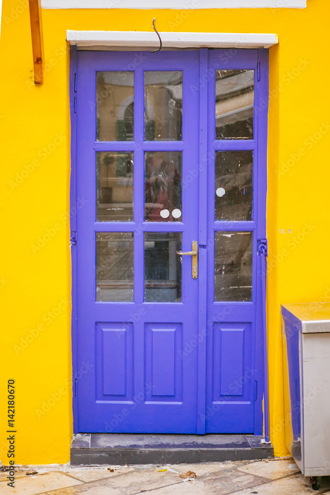 Purple door with glass on the yellow wall