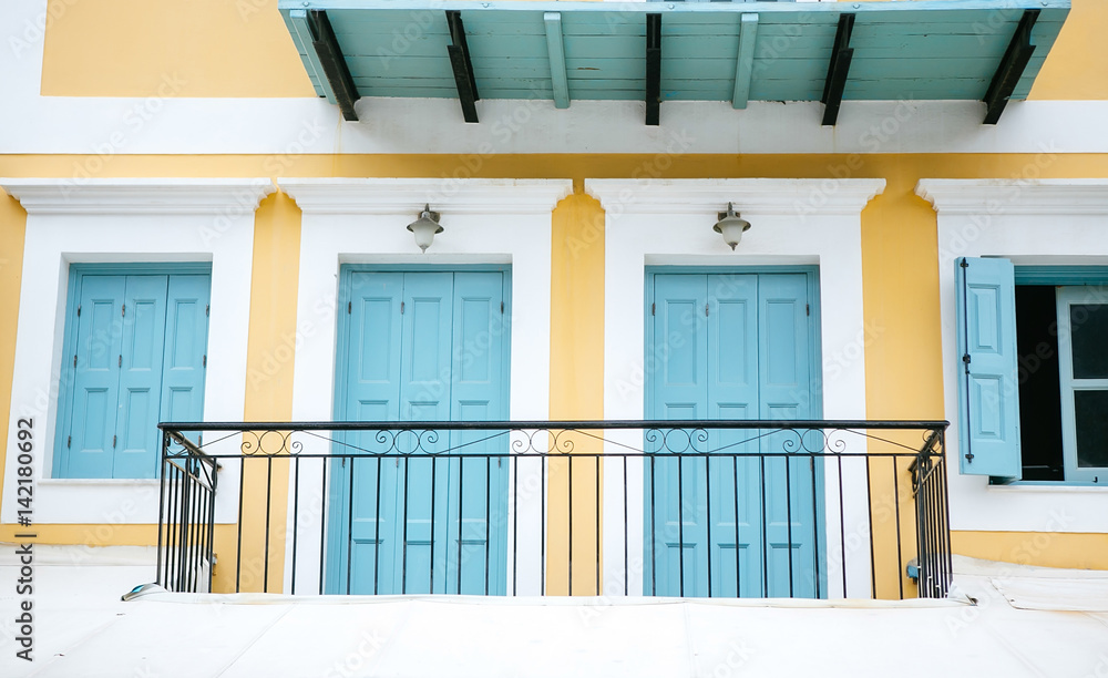Naklejka premium Balcony on the yellow house with turquoise doors and windows