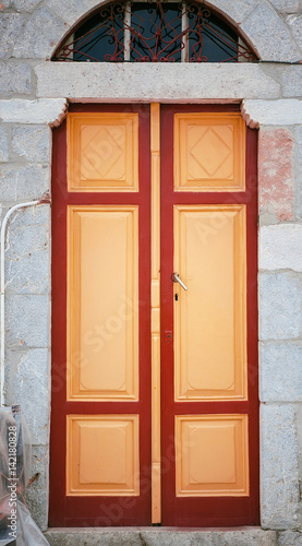 Red and yellow wooden door on a stone wall