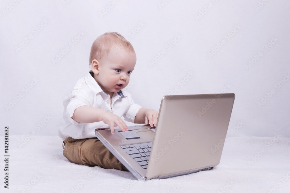 Concentrated baby boy playing or programming on laptop. Concept of new it generation Concentrated baby boy playing or programming on laptop. Concept of new it generation