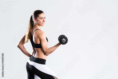 Strong fit young woman with dumbbell isolated.