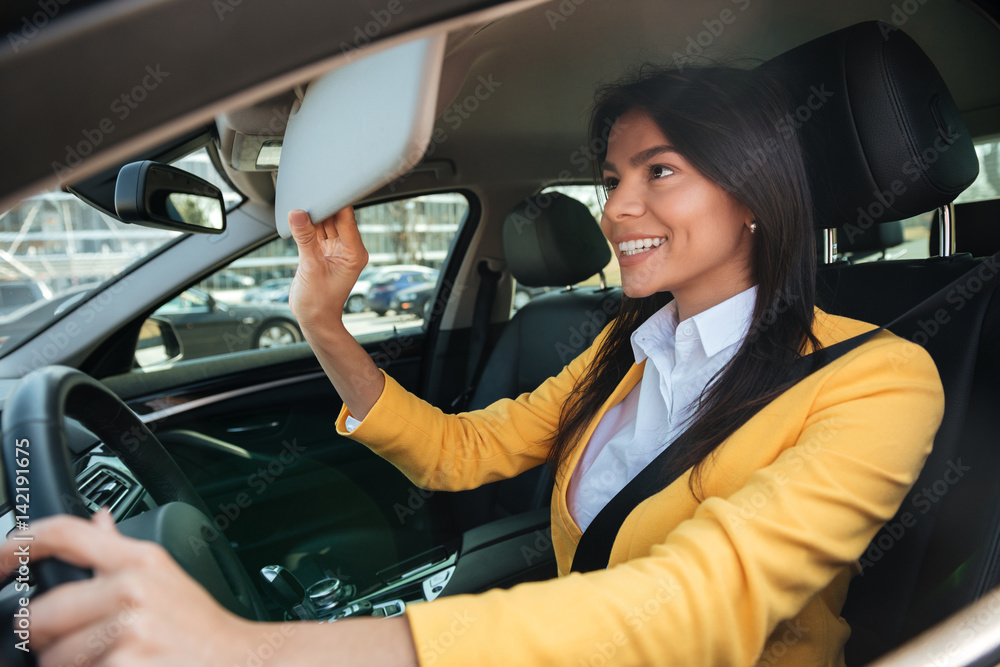 Young business woman looking in mirror while driving car