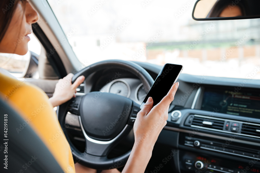 Young woman driver using touch screen smartphone