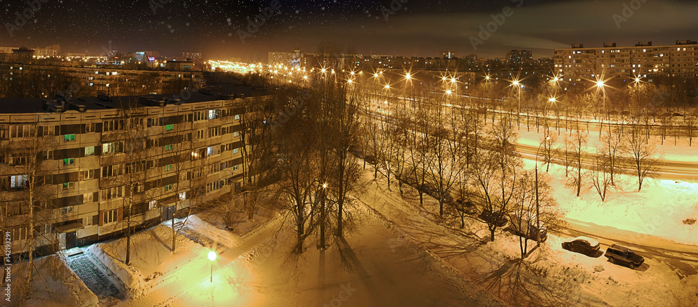 Panorama of night city under falling snow