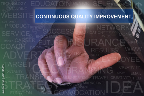 Businessman touching CONTINUOUS QUALITY IMPROVEMENT button on virtual screen