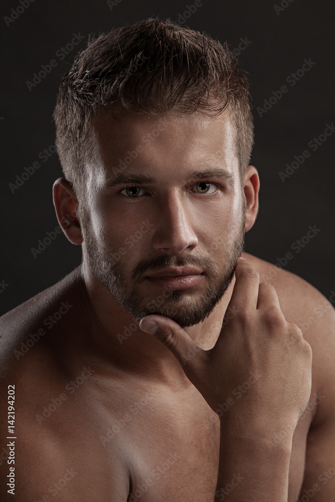 Model man with an open chested on a dark background , muscular body of a young man in jeans . Shot in a studio . Model man with an open chested on a dark background , muscular body of a young man in jeans . Shot in a studio .