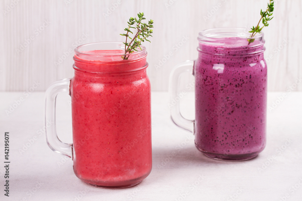 Summer berries smoothie in the jars on white rustic background Summer berries smoothie in the jars on white rustic background