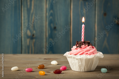 Homemade Birthday cupcake with candle and colorful candies
