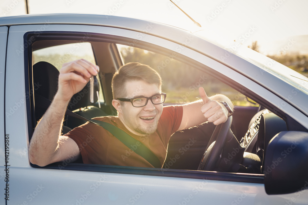 Naklejka premium Attractive young man showing his new car keys and smiling