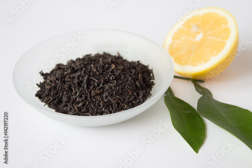 Dry tea in a beautiful bowl and lemon with green leaves