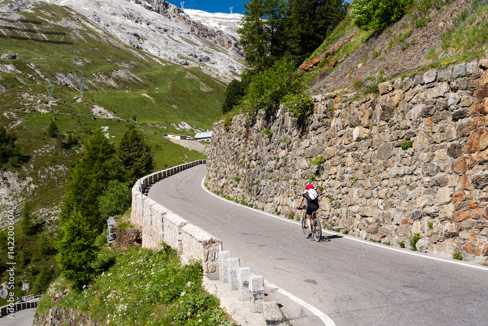 Biker rides serpentine mountain road in Tyrol alps, Italy