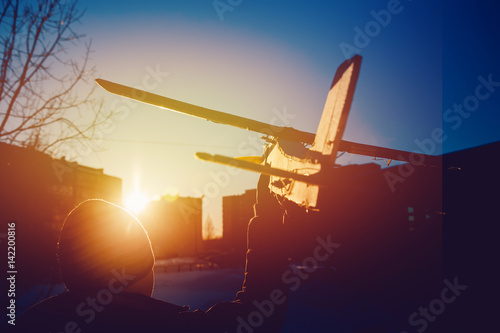 plane is on the radio control, the guy is holding the plane in his hand at sunset. Run the model airplane. Winter