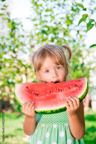 Little blonde girl with big slice watermelon in summer time in park, outdoor. Surprise child. Oops, wow.