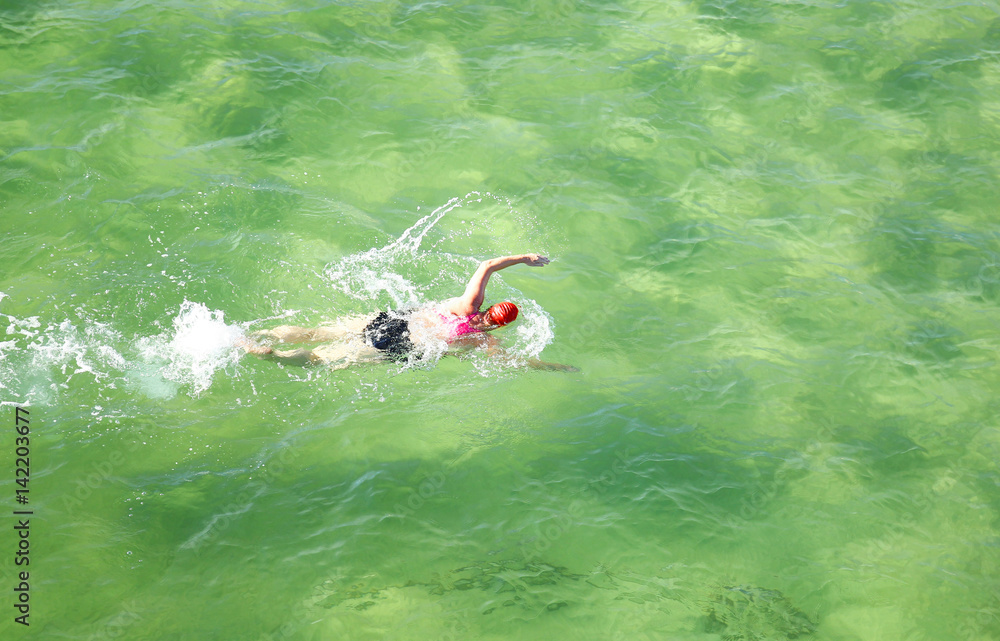 Lady swimmer wearing a swim cap having a workout in the beautiful ocean