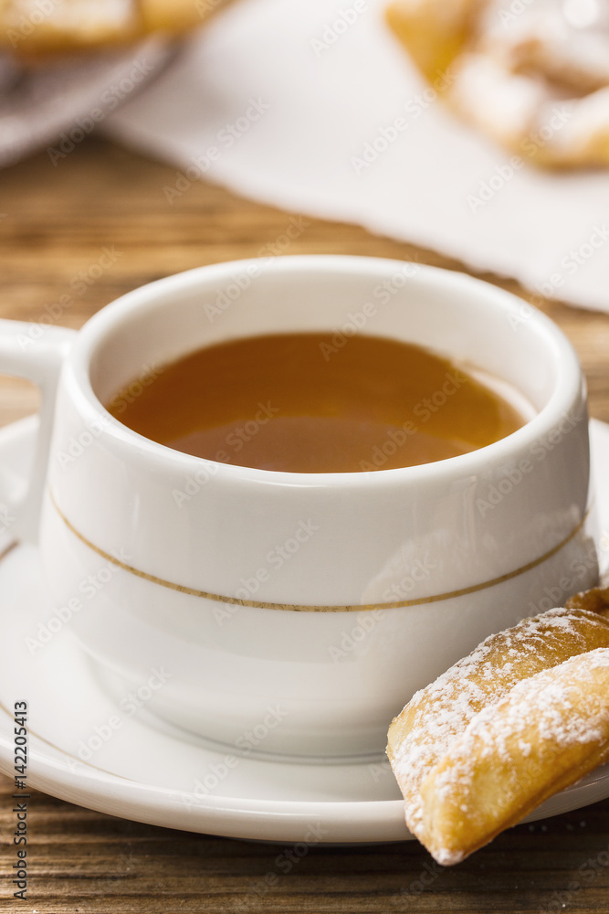 Elegant tea cup and faworek for a dessert Elegant tea cup and faworek for a dessert