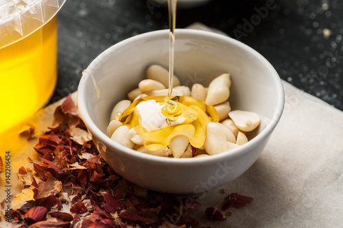 Peeled raw peanuts in a white ceramic bowl poured with thin honey trickle