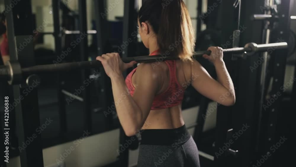 Sport woman squat with barbell in gym Sport woman squat with barbell in gym