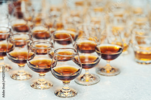 Row of glasses with whiskey or cognac on the table. Strong alcohol in a bar or restaurant.