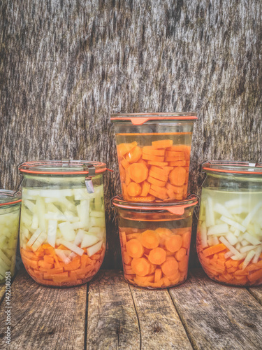 Einmachgläser mit Karotten und Kohlrabi vor Holzplatte