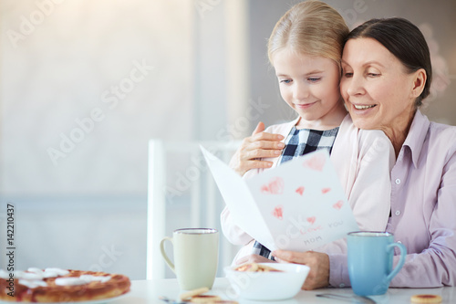 Happy girl and mature woman reading greetings for women day