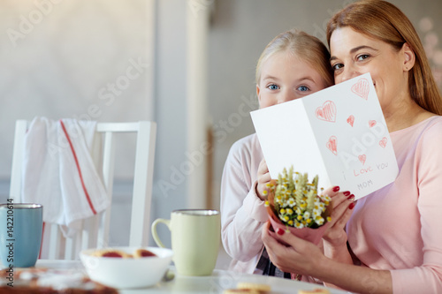 Woman and her daughter holding flowers and handmade greeting-card