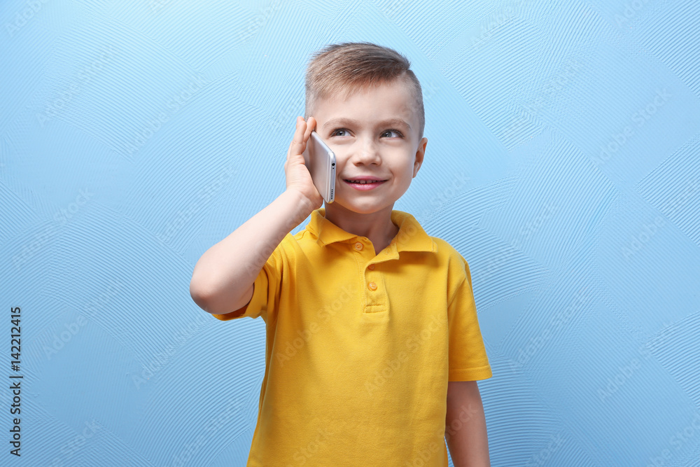 Cute little boy talking by mobile phone on color background Cute little boy talking by mobile phone on color background