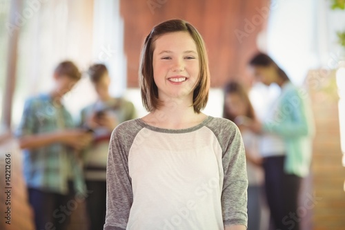 Portrait of smiling schoolgirl standing in corridor