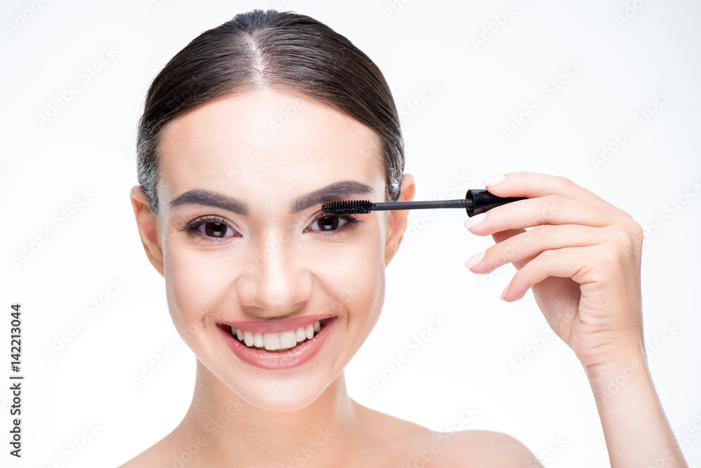 Woman painting eyelashes by mascara Woman painting eyelashes by mascara