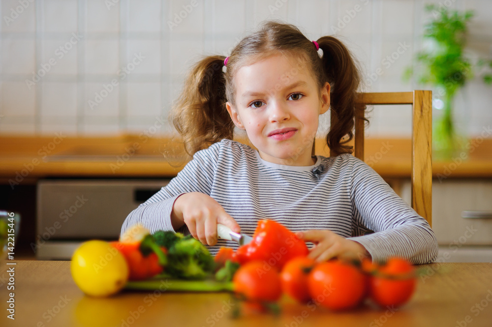 Girl 8-9 years old in the kitchen slicing vegetables for a salad.