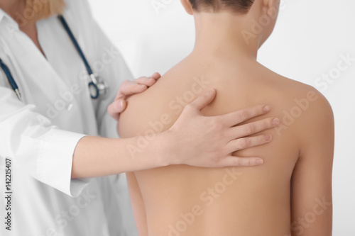 Incorrect posture concept. Physiotherapist examining and correcting boy's back © Africa Studio