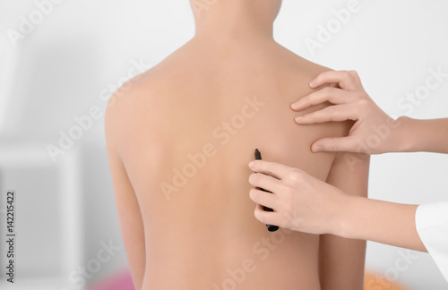 Incorrect posture concept. Physiotherapist examining and correcting boy's back