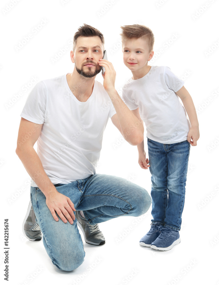 Little boy and his father talking by mobile phone, on white background