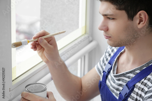 Young worker painting windo...