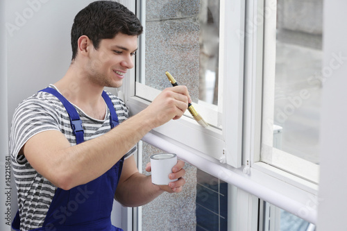 Young worker painting windo...