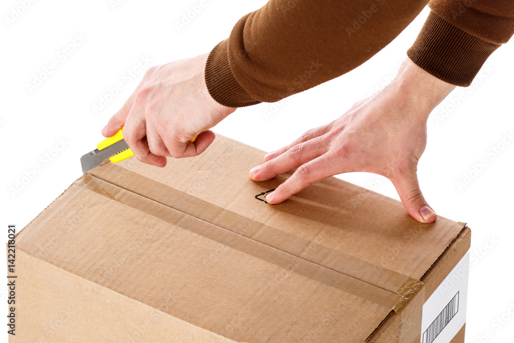 The man opens the box with a sharp cutting knife. Close-up. Isolated on white background The man opens the box with a sharp cutting knife. Close-up. Isolated on white background
